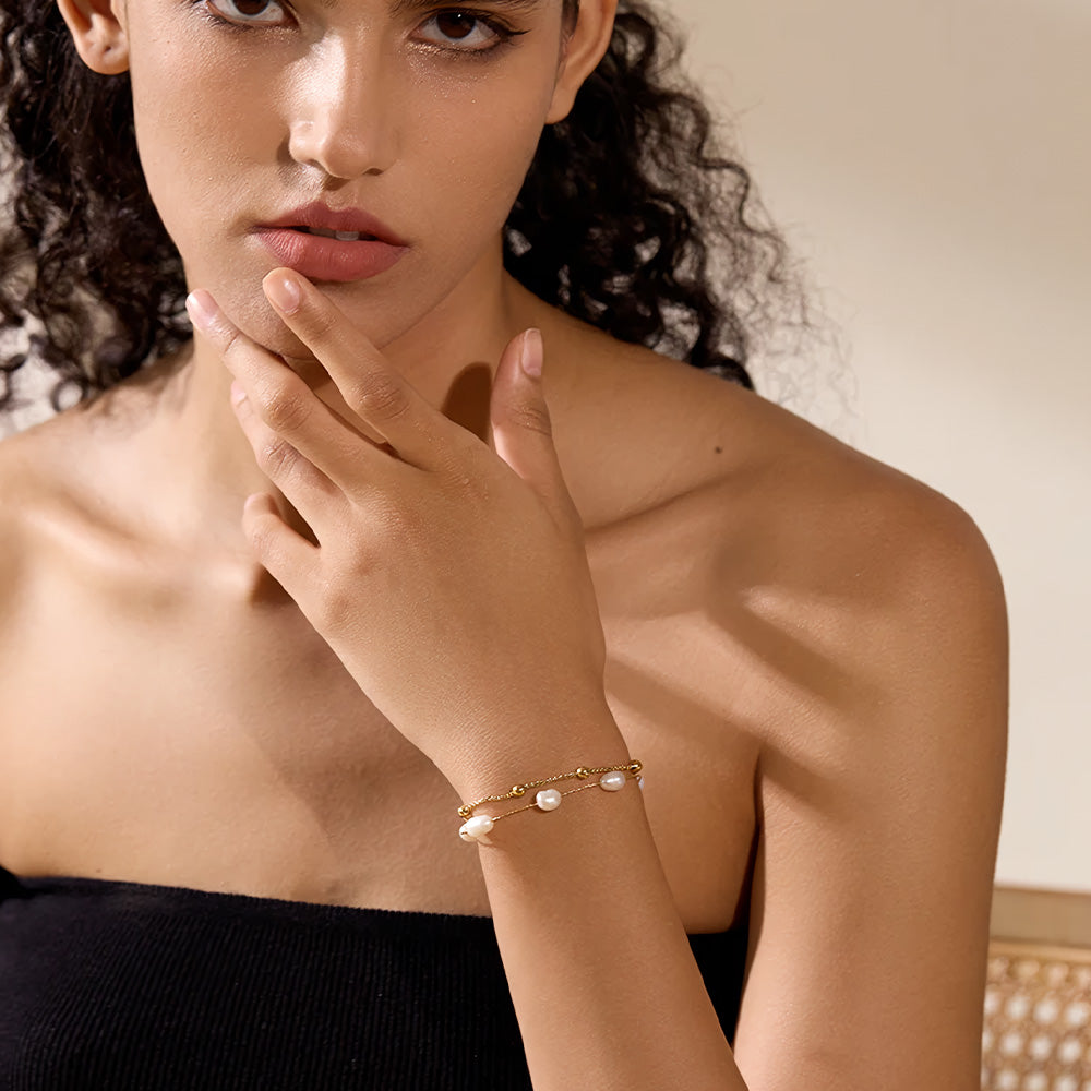 Foto distante da modelo usando a Pulseira Feminina Dourada de Pérolas Naturais Dupla - Banhada a Ouro 18k