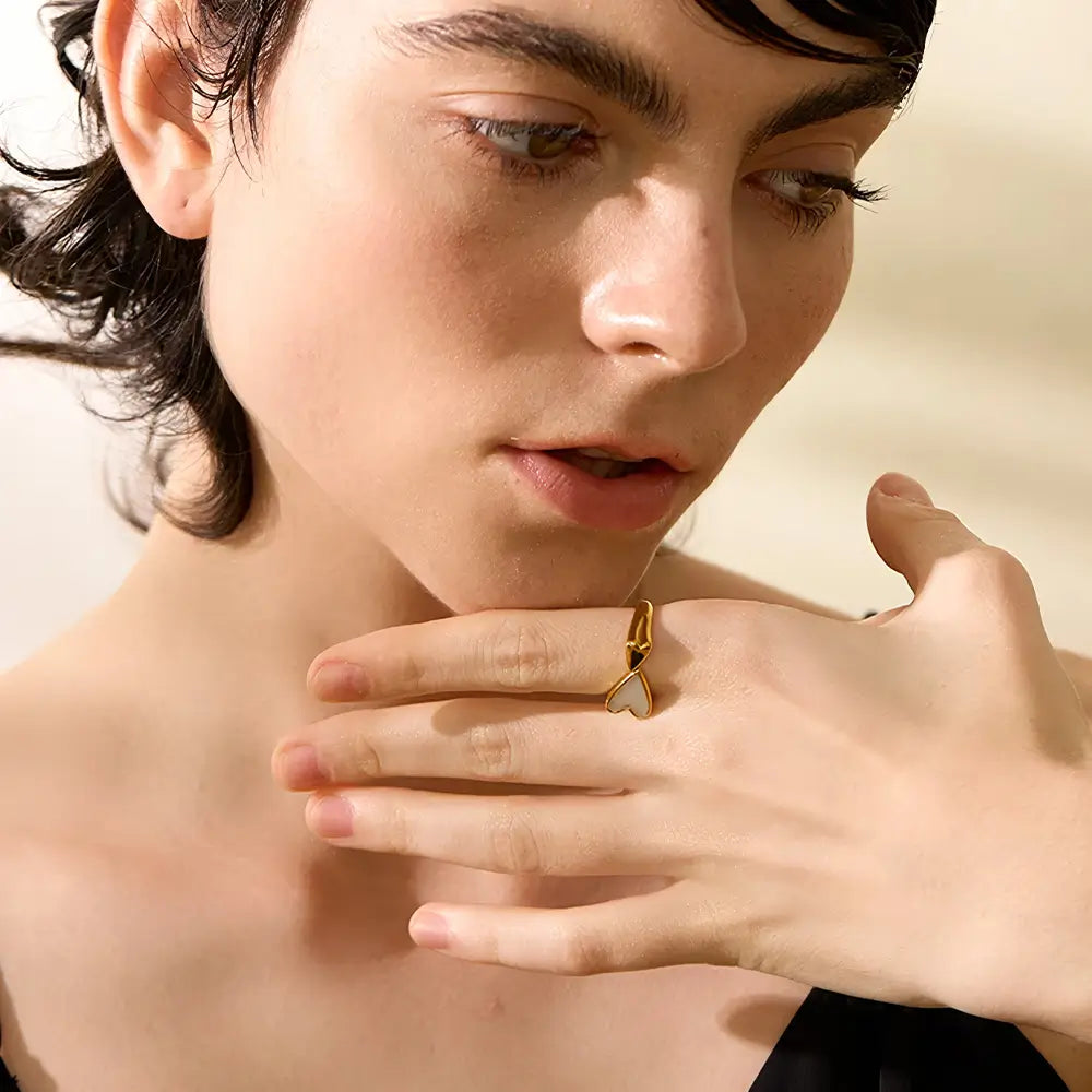 Foto da mão de uma mulher usando o Anel Feminino Dourado Ajustável com Coração de Concha Natural Coralina - Banhado a Ouro 18k