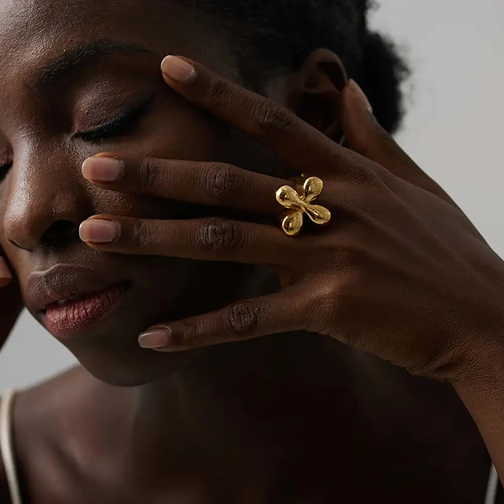 Foto de média distância de uma Mulher negra usando o Anel Feminino Dourado Gota Cruzada Gotalia - Banhado a Ouro 18k