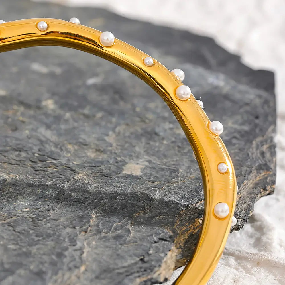 Bracelete Dourado Feminino cravejado com pérolas Alina em cenário neutro e sofisticado