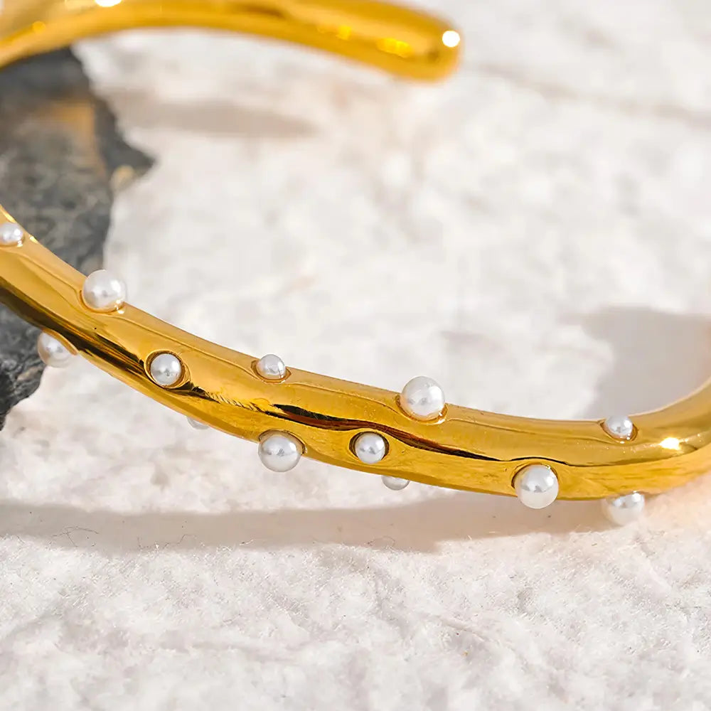 Bracelete Dourado Feminino cravejado com pérolas e design fino em ambiente minimalista