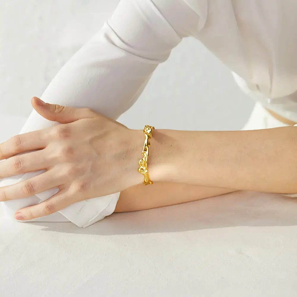 Bracelete Dourado Feminino rígido aberto irregular com estrutura marcante e toque artístico