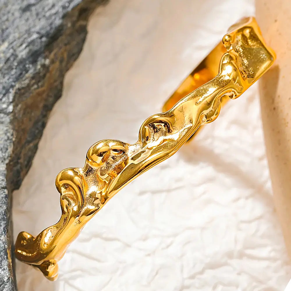 Bracelete Dourado Feminino rígido aberto irregular com destaque para o brilho em fundo claro