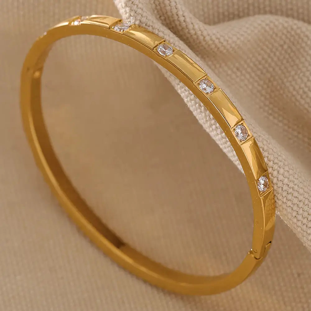 Bracelete Feminino Dourado fino cravejado com zircônias em fundo neutro e luz suave