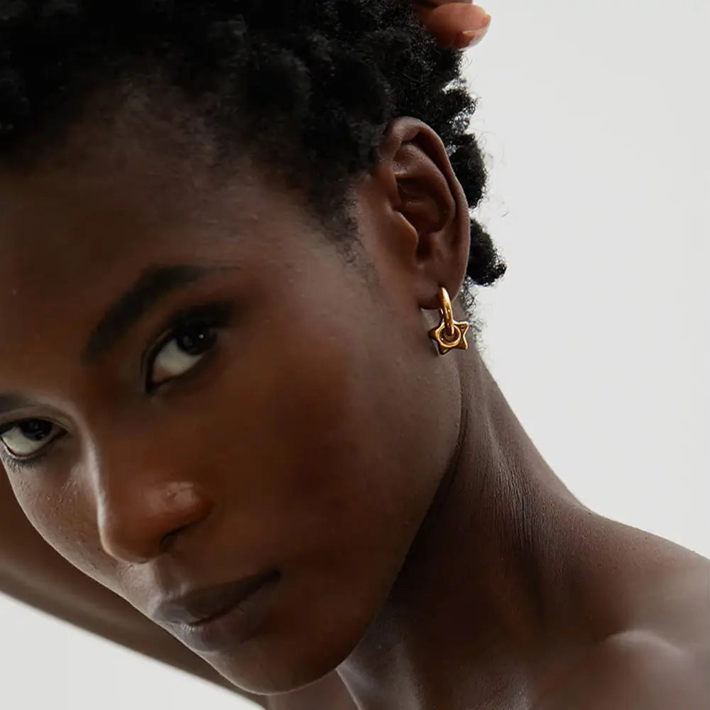 Mulher usando o Brinco Argola Feminino Dourado com Pingente de Estrela Estelari - Banhado a Ouro 18k