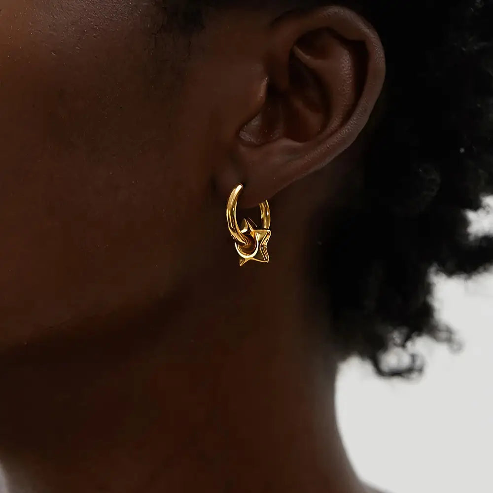 Mulher usando o Brinco Argola Feminino Dourado com Pingente de Estrela Estelari - Banhado a Ouro 18k
