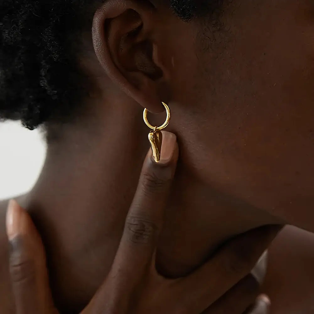 Mulher usando o Brinco Argola Feminino Dourado com Pingente de Coração Coraelle - Banhado a Ouro 18k