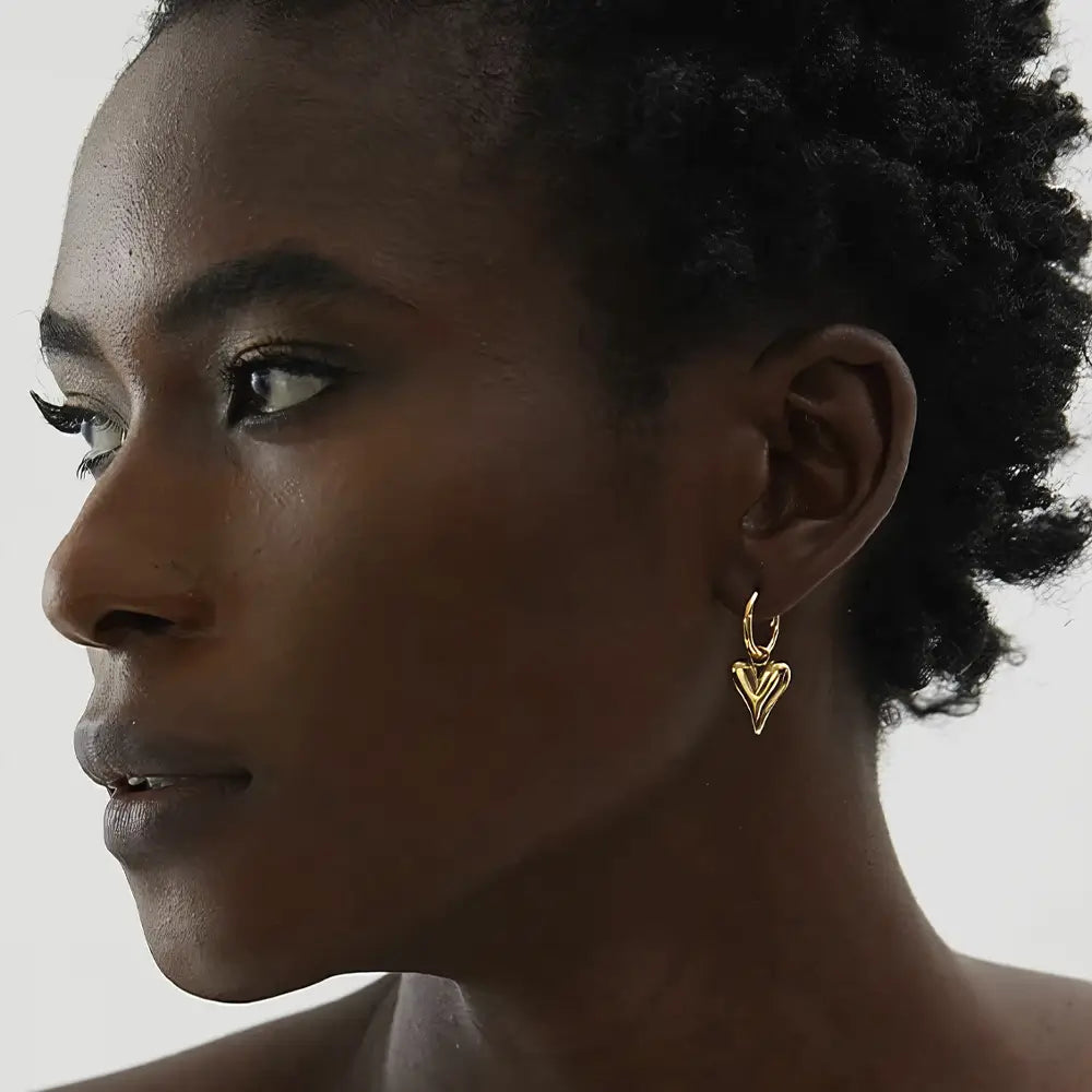 Mulher usando o Brinco Argola Feminino Dourado com Pingente de Coração Coraelle - Banhado a Ouro 18k