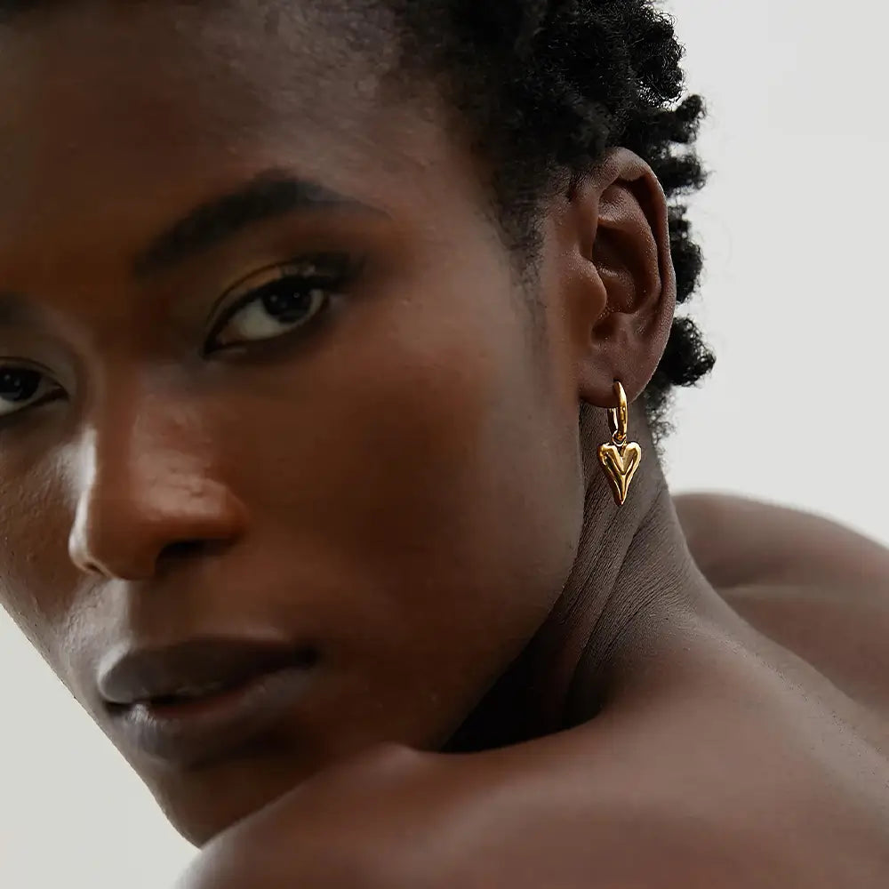 Mulher usando o Brinco Argola Feminino Dourado com Pingente de Coração Coraelle - Banhado a Ouro 18k