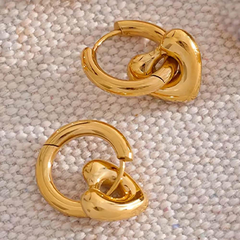 Brinco Feminino Argola Dourada com pingente de coração em cenário minimalista