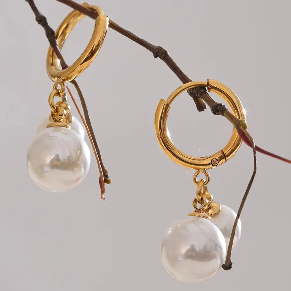 Brinco Feminino Argola Dourada com pingente de pérola, estilo minimalista em cenário suave