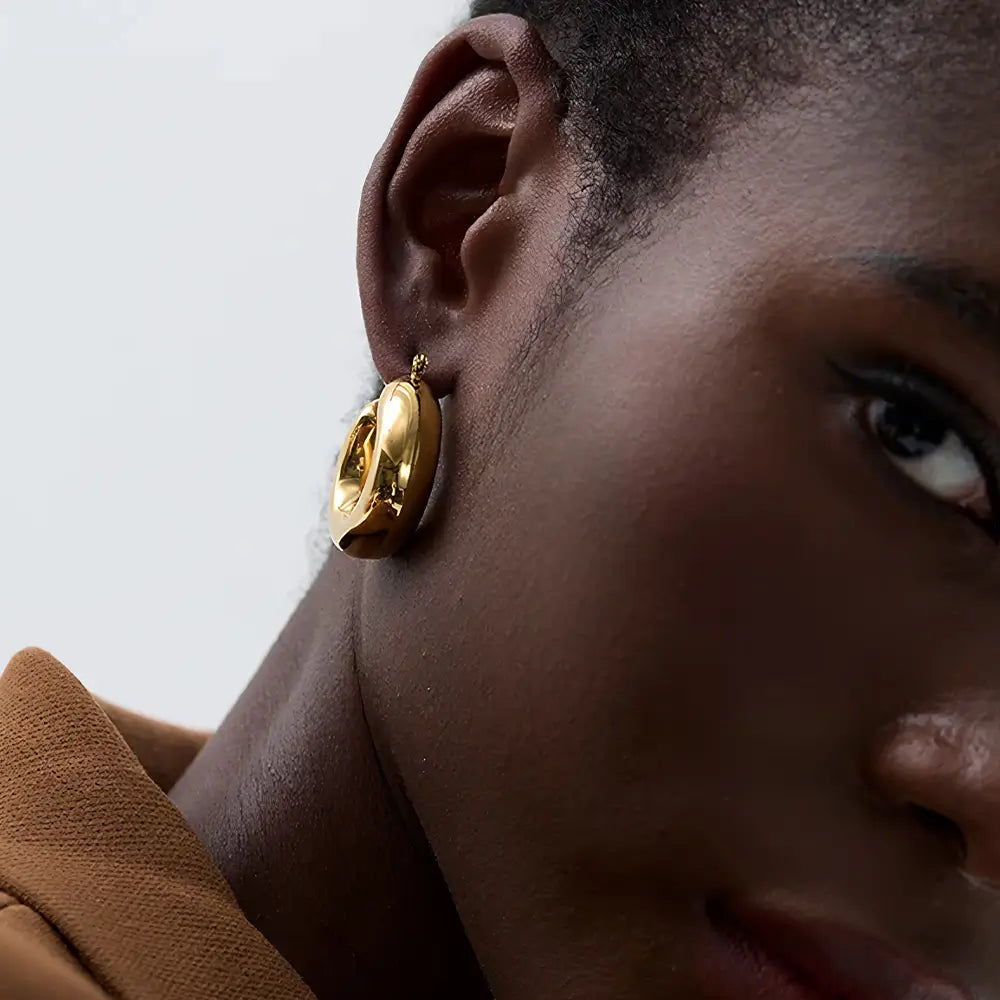 Foto frontal de perto da Mulher usando o Brinco Feminino Argola Dourada Grossa Chunky Véria - Banhado a Ouro 18k