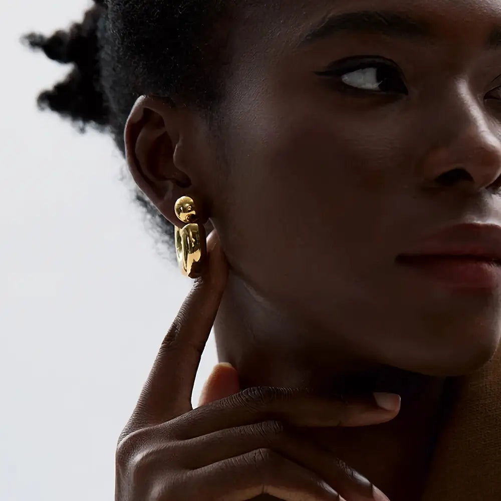 Foto de lado de uma Mulher usando o Brinco Feminino Argola Dourada Grossa Tipo C Thessa - Banhado a Ouro 18k