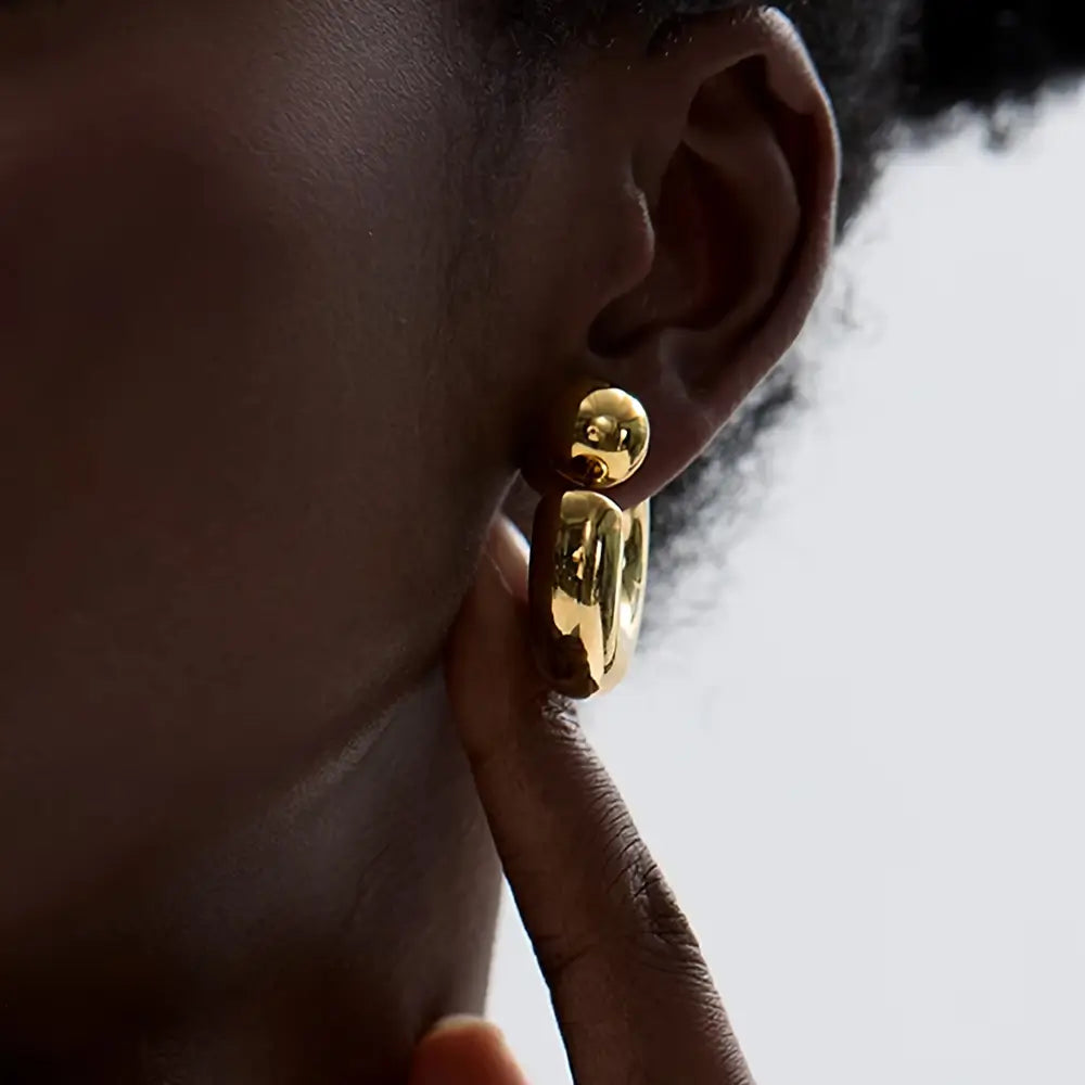 Foto de perto de uma Mulher usando o Brinco Feminino Argola Dourada Grossa Tipo C Thessa - Banhado a Ouro 18k