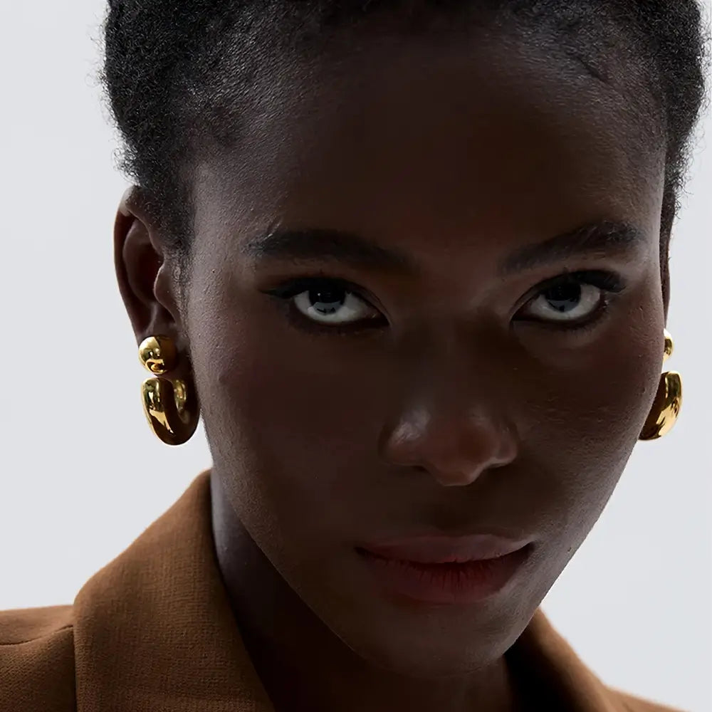 Foto de frente de uma mulher usando o Brinco Feminino Argola Dourada Grossa Tipo C Thessa - Banhado a Ouro 18k