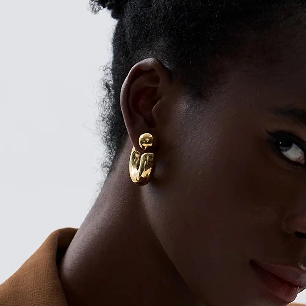 Foto próxima de lado de uma Mulher usando o Brinco Feminino Argola Dourada Grossa Tipo C Thessa - Banhado a Ouro 18k