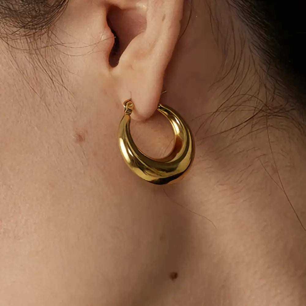 Foto de perto de uma Mulher usando o Brinco Feminino Argola Dourada Larga Meia Lua Selene - Banhado a Ouro 18k