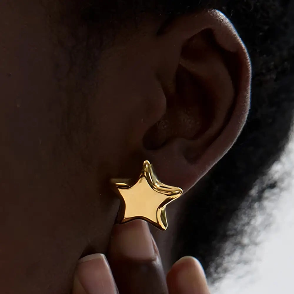 Brinco Feminino Dourado estrela Stella com acabamento sofisticado e polido, foto de perto da modelo usando
