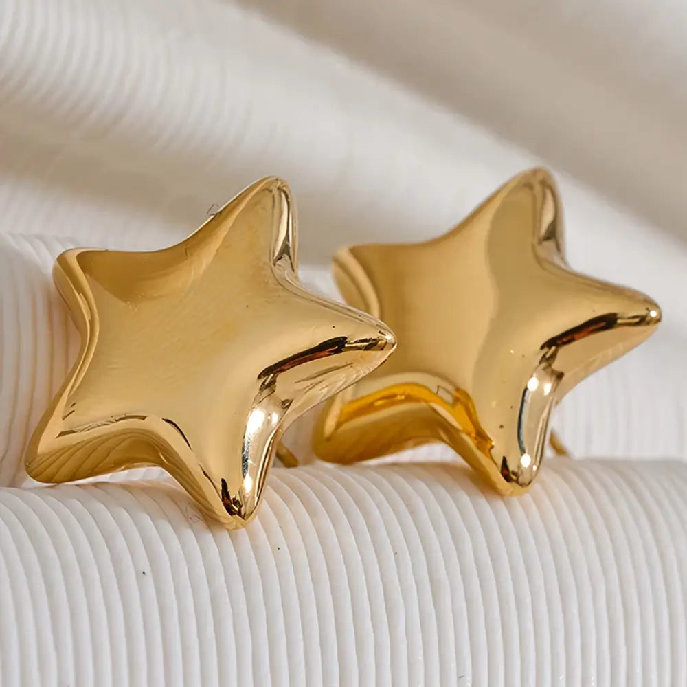 Brinco Feminino Dourado Stella com estrela polida em fundo neutro