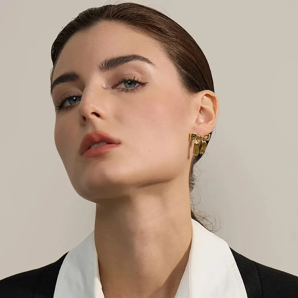 Brinco Feminino Dourado laço com textura refinada e toque romântico, mulher usando