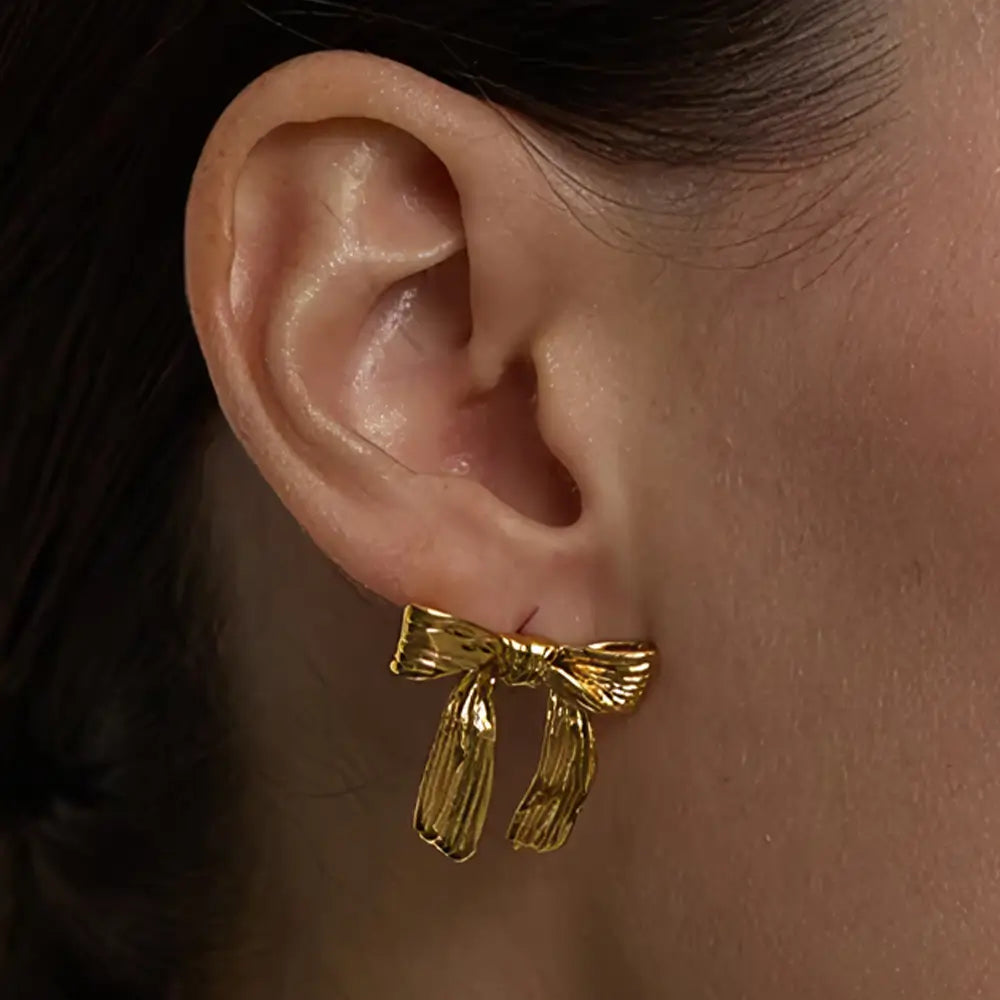 Foto de perto da modelo usando o Brinco Feminino Dourado laço Seraphine com acabamento elegante e detalhado