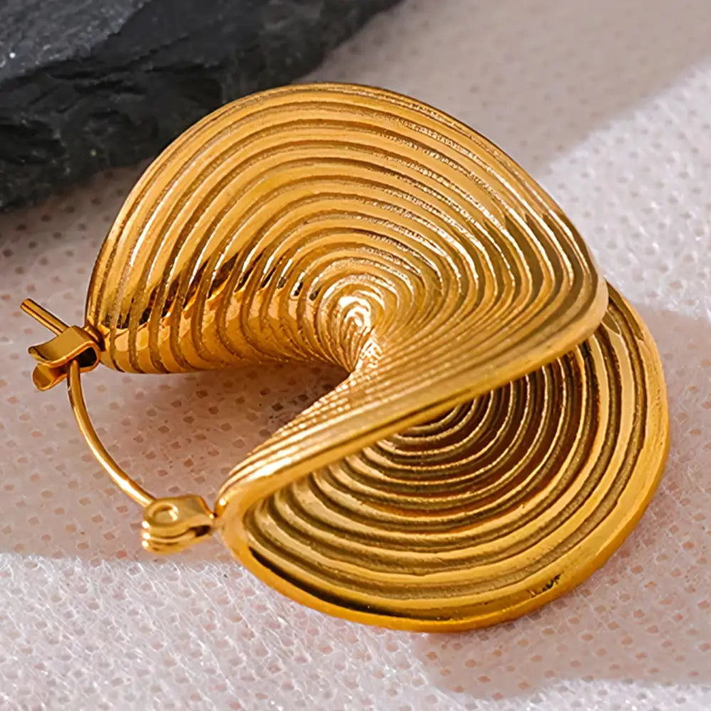Brinco Feminino Dourado minimalista circular com textura polida em fundo neutro