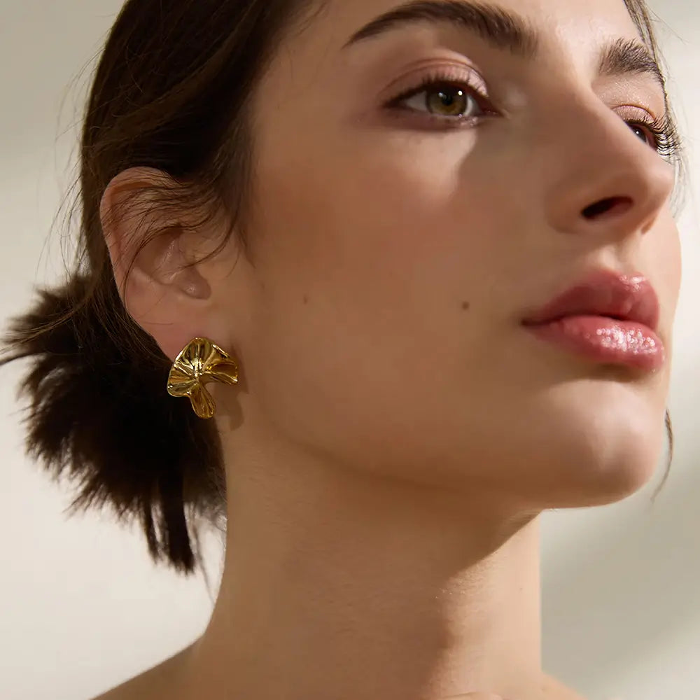 Brinco Feminino Dourado ondulado minimalista com curvas suaves e banho em ouro 18k, modelo usando