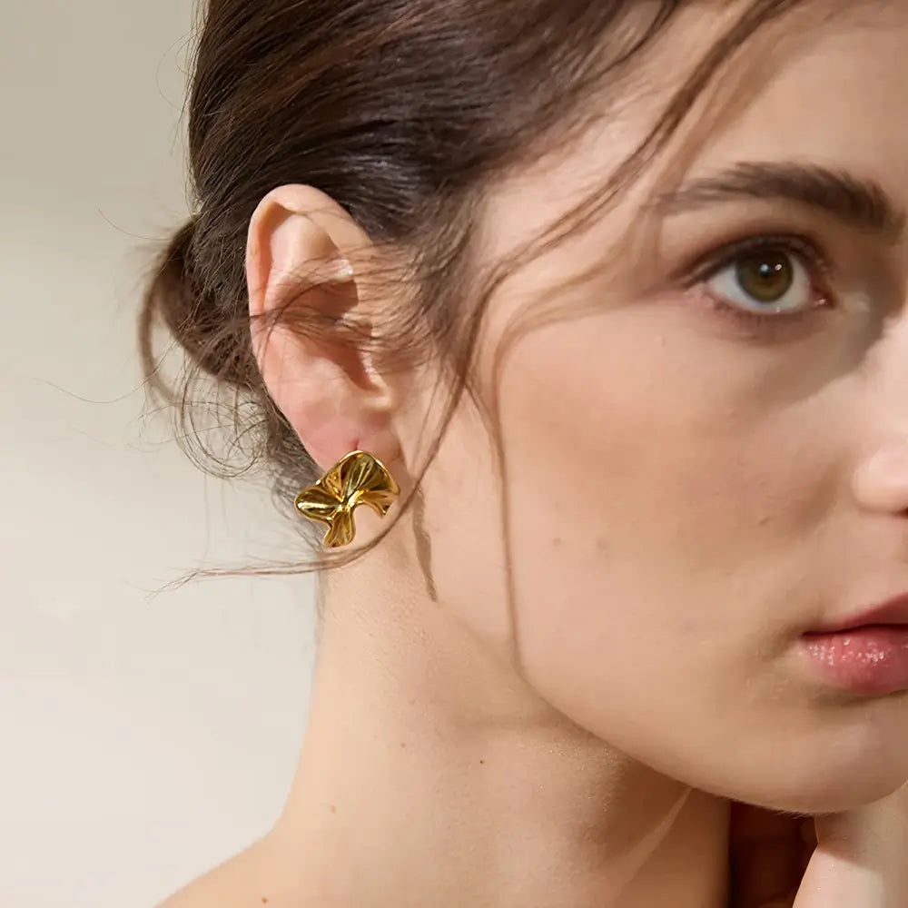 Brinco Feminino Dourado ondulado com formato assimétrico e visual contemporâneo, modelo usando