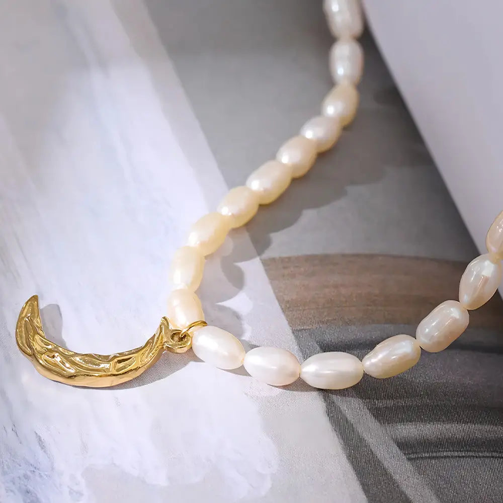 Colar Feminino de pérolas naturais com pingente meia lua dourada Celine em fundo neutro e iluminação natural