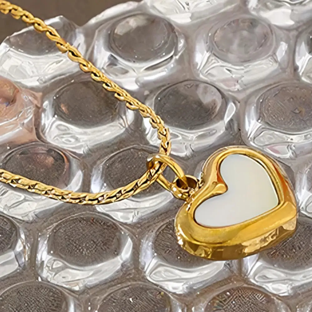 Colar Feminino Dourado de coração com concha natural Marena sobre fundo neutro e iluminação suave