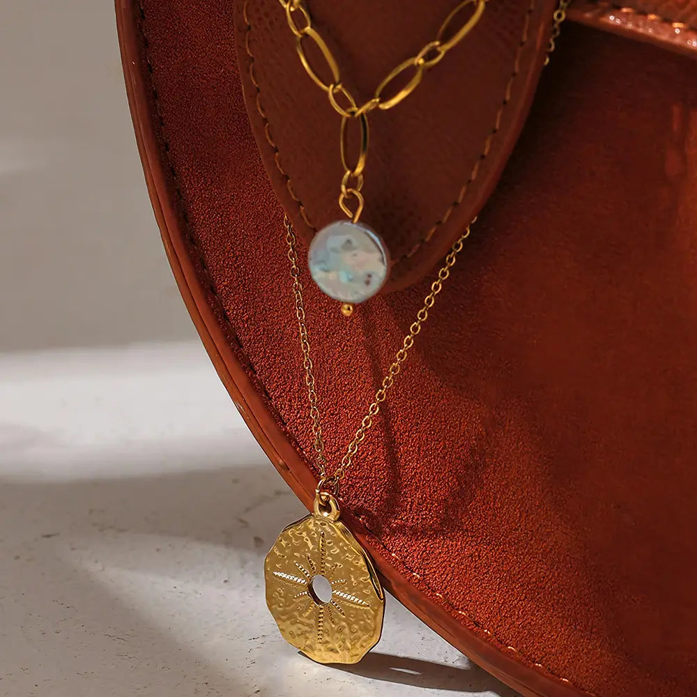 Colar Feminino Dourado duplo com pérola natural e estrela do norte Estelle em cenário minimalista e iluminação suave