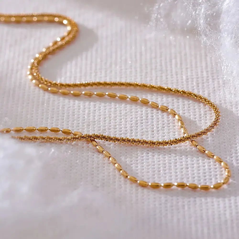 Colar Feminino Dourado duplo corrente torcida e contas Elara com design elegante sobre fundo claro