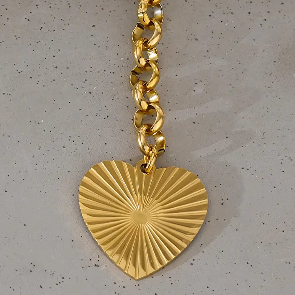 Colar Feminino Dourado elo português com acabamento brilhante e coração dourado em cenário minimalista