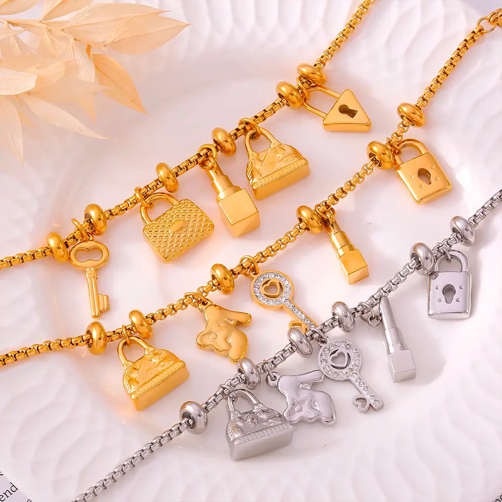 Pulseira Berloques em Aço Inox Dourada Feminina de Cadeado, Bolsa, Batom e Chave Luxelle - Banhada a Ouro 18k, fundo neutro