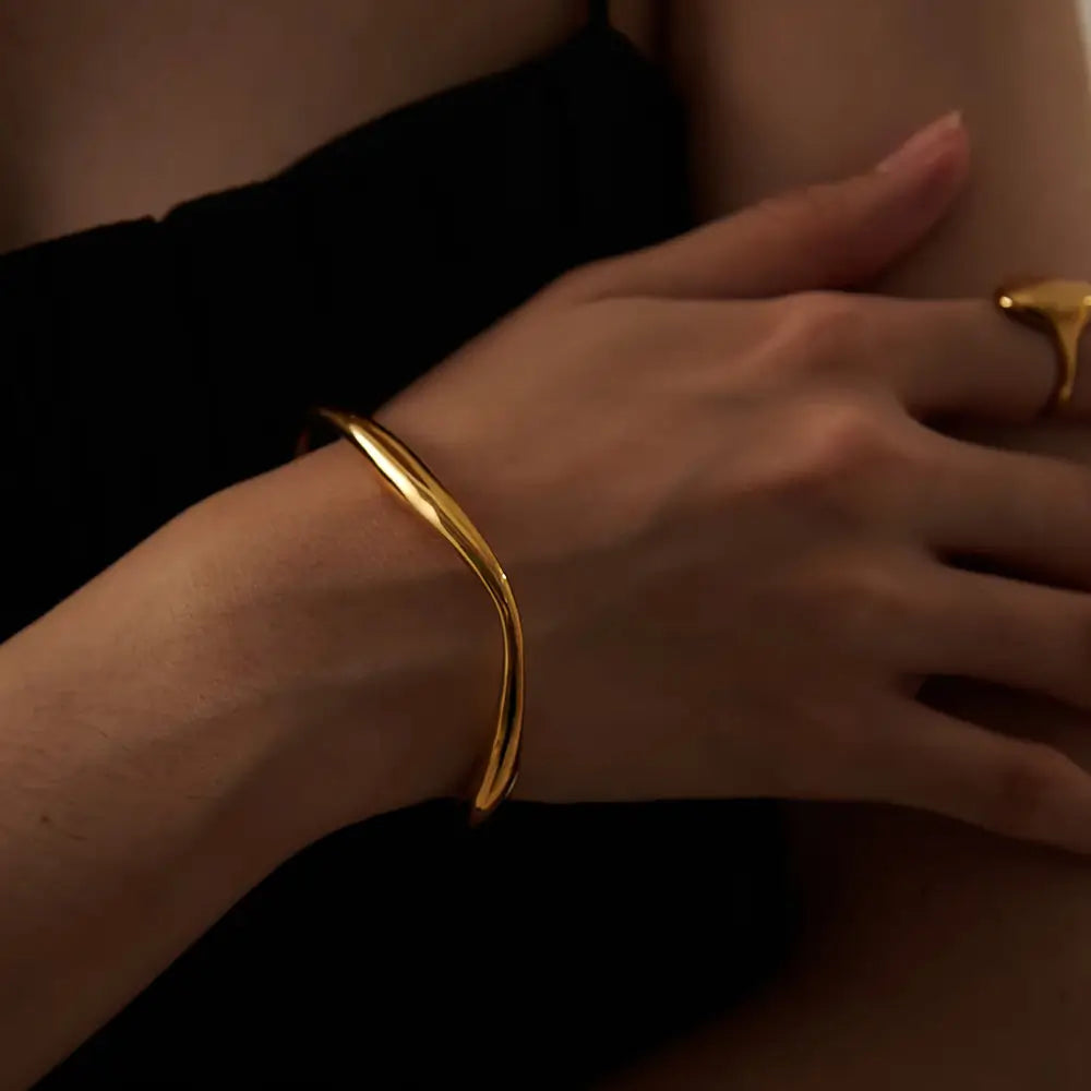 Foto de perto de uma Mulher usando a Pulseira Feminina Dourada Cuff Irregular Ajustável Aurora - Banhada a Ouro 18k