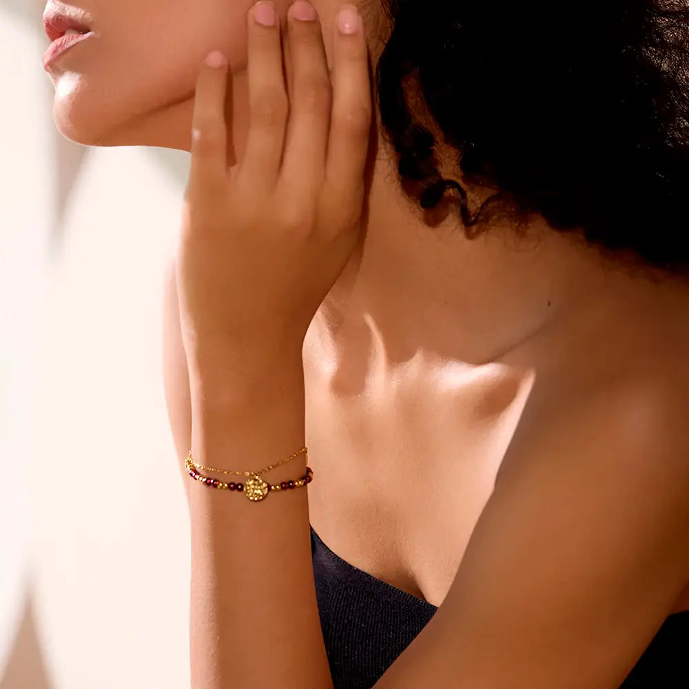 Foto do braço de uma modelo usando a Pulseira Feminina Dourada Dupla de Pedras Naturais e Pingentes Aurélianne - Banhada a Ouro 18k