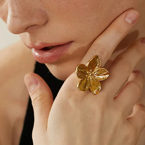 Foto de perto de uma Mulher usando o Anel Feminino Dourado Flor de 5 Pétalas Ajustável Florença - Banhado  a Ouro 18k com as mão no rosto