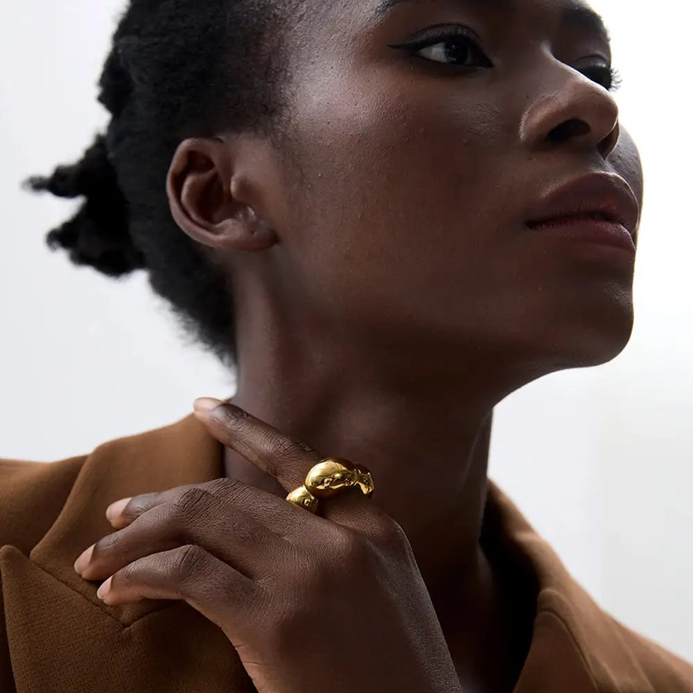Mulher usando o Anel Feminino Dourado Flor Oca Fiorella - Banhado a Ouro 18k, foto de perto, mão no pescoço