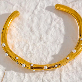 Bracelete Dourado Feminino cravejado com pérolas ajustável com toque clássico em fundo discreto