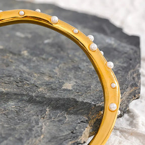 Bracelete Dourado Feminino cravejado com pérolas Alina em cenário neutro e sofisticado