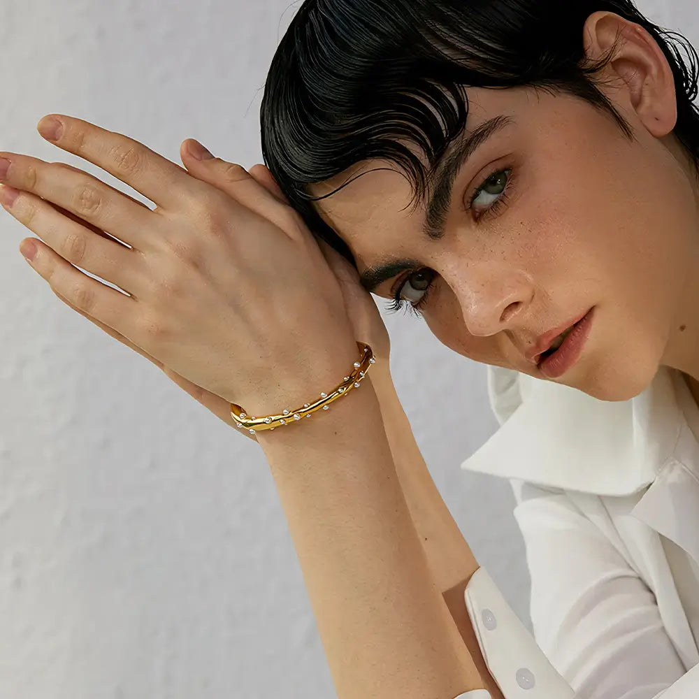 Bracelete Dourado Feminino cravejado com pérolas e brilho delicado no pulso