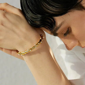 Bracelete Dourado Feminino cravejado com pérolas e estrutura leve e luxuosa