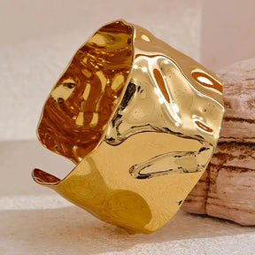 Bracelete Dourado Feminino largo grosso ondulado com design contemporâneo em fundo neutro