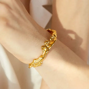 Bracelete Dourado Feminino rígido aberto com design assimétrico e acabamento polido
