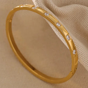 Bracelete Feminino Dourado fino cravejado com zircônias em fundo neutro e luz suave