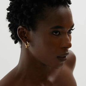 Mulher usando o Brinco Argola Feminino Dourado com Pingente de Estrela Estelari - Banhado a Ouro 18k