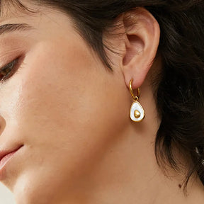 Foto lateral de perto da Mulher usando o Brinco Feminino Argola Dourada com Pingente de Abacate de Concha Natural Amara - Banhado a Ouro 18k