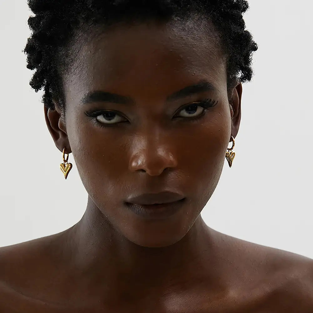 Mulher usando o Brinco Argola Feminino Dourado com Pingente de Coração Coraelle - Banhado a Ouro 18k