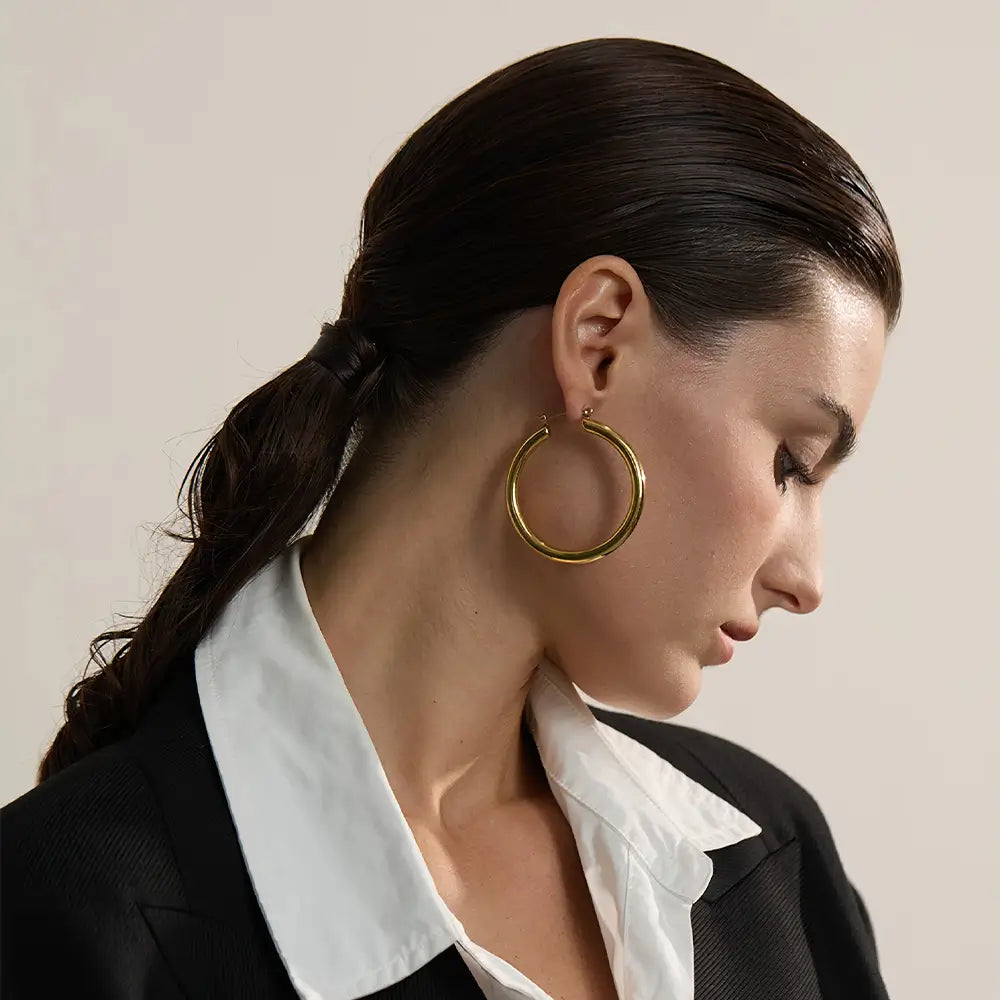 Brinco Feminino Argola Dourada grande com design minimalista e brilho sofisticado, modelo usando