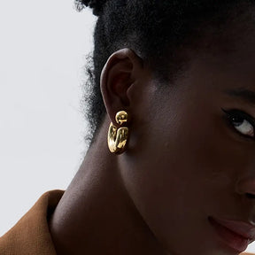 Foto próxima de lado de uma Mulher usando o Brinco Feminino Argola Dourada Grossa Tipo C Thessa - Banhado a Ouro 18k